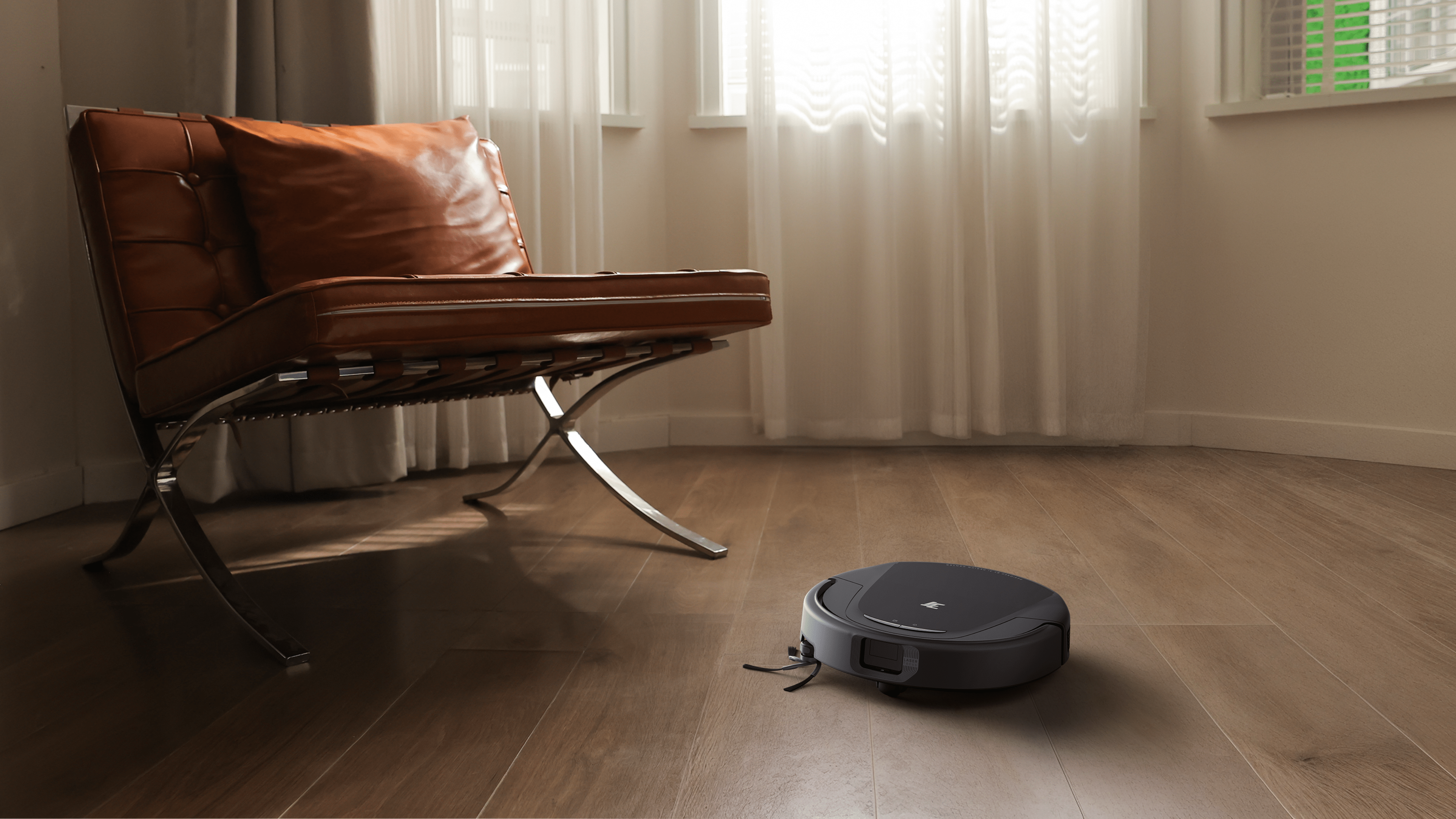 Ein Roboterstaubsauger auf einem Holzboden neben einem modernen Stuhl in einem gut beleuchteten Raum.