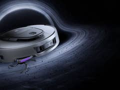 Ein Saugroboter schwebt im Weltraum in der Nähe eines wirbelnden schwarzen Lochs.