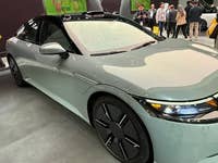 Ein elegantes, modernes Auto, das auf einer Automesse mit einer Menge im Hintergrund ausgestellt ist.