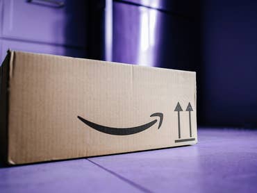 Ein Pappkarton mit dem Amazon-Logo auf einem lila Boden.