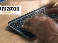 Hände tippen auf einer Logitech MX Keys Mini Tastatur auf einer Holzoberfläche mit einem Amazon-Logo.