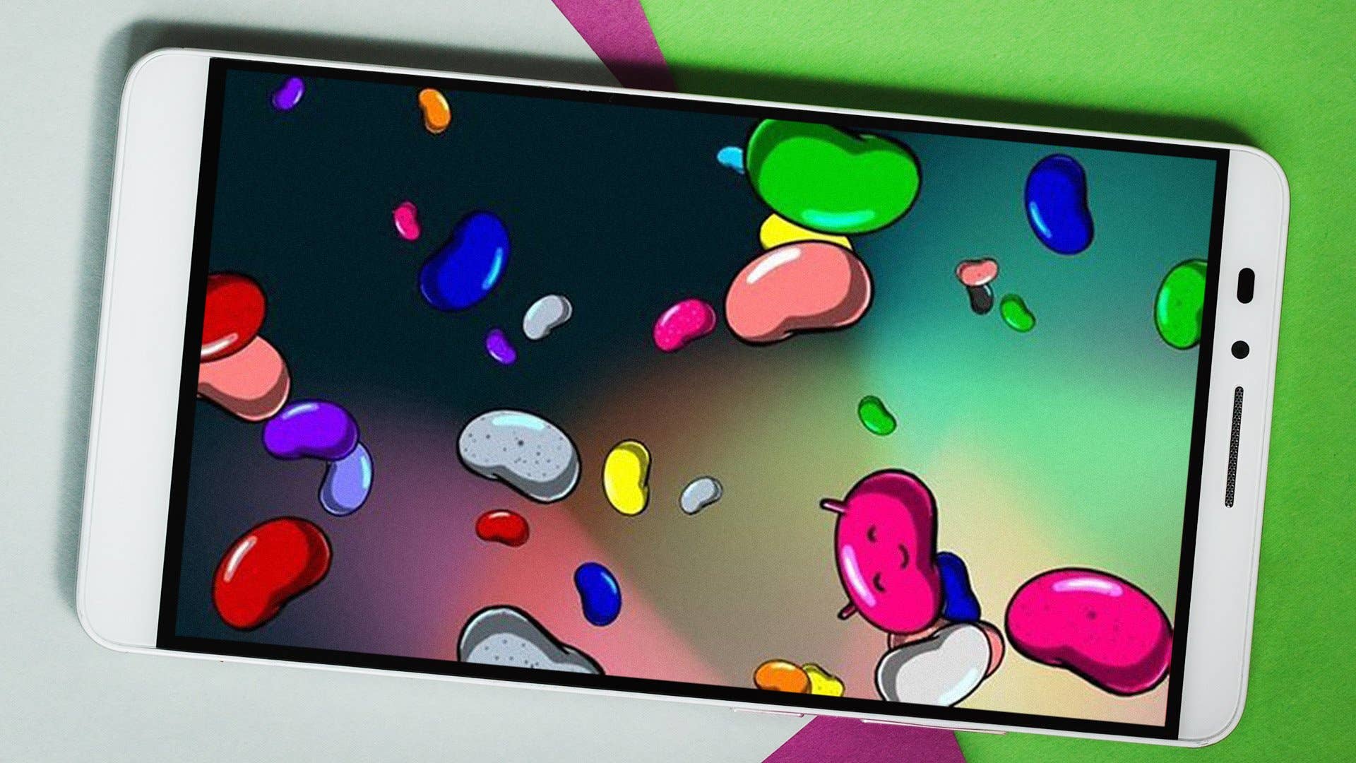 Ein Smartphone zeigt bunte Jelly Beans auf dem Bildschirm vor einem grünen und pinken Hintergrund. Ein Smartphone zeigt bunte Jelly Beans auf dem Bildschirm vor einem grünen und pinken Hintergrund.