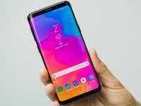 Eine Person hält ein Samsung Galaxy S9 Smartphone, das einen bunten Startbildschirm zeigt.