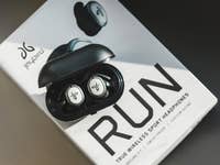 True Wireless-Sportkopfhörer in einem Ladeetui auf einer Box mit der Aufschrift 'RUN'.