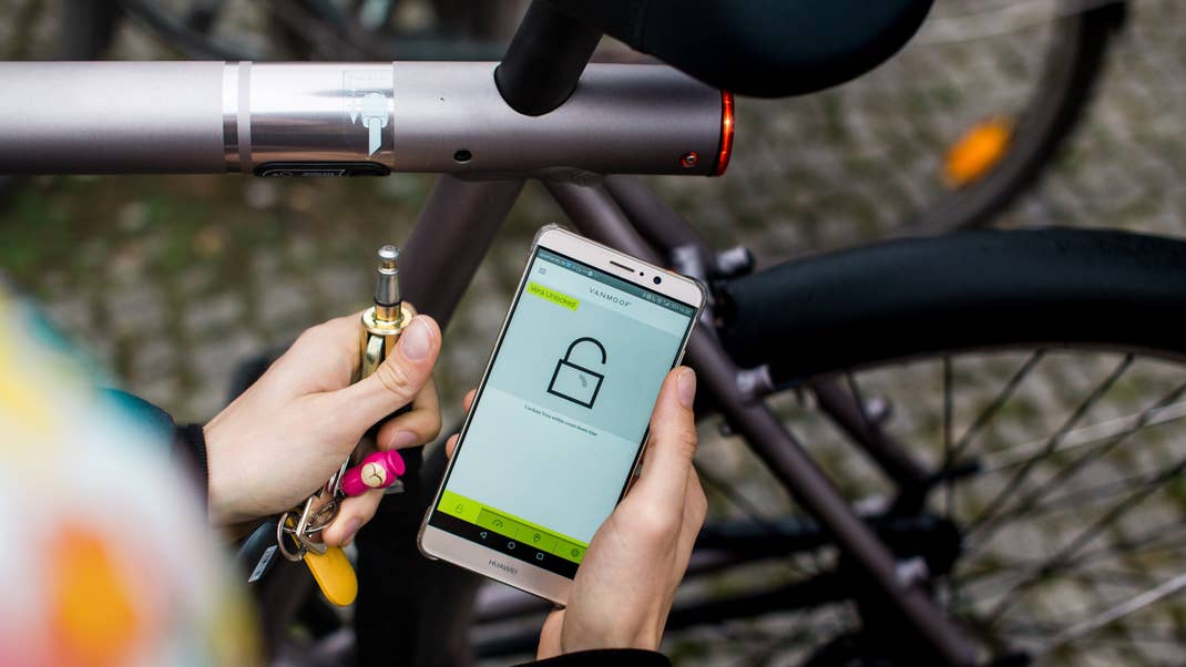 Eine Person verwendet ein Smartphone, um ein VanMoof Electrified S Fahrrad zu entsperren.