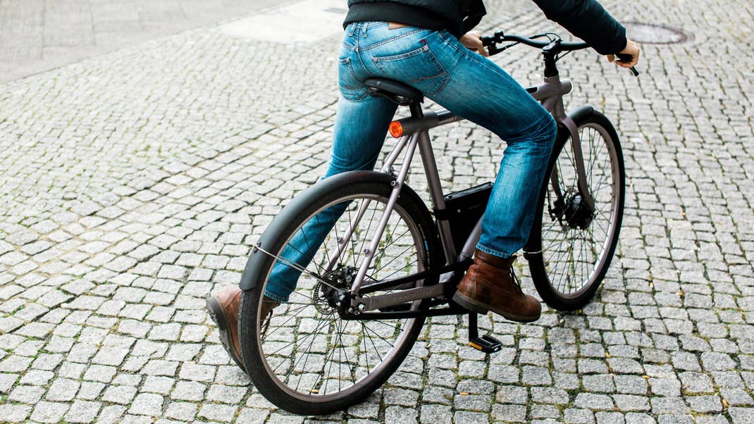 Eine Person fährt ein VanMoof Electrified S Fahrrad auf einer Kopfsteinpflasterstraße.