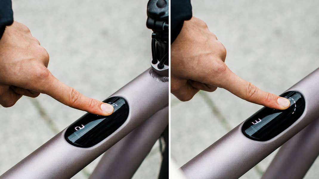 Eine Hand drückt einen Knopf am Rahmen eines VanMoof Electrified S Bikes.