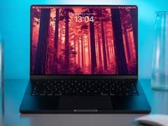 Ein MacBook Pro auf einem Tisch, das einen Wald-Hintergrund mit der Uhrzeit 13:04 anzeigt.