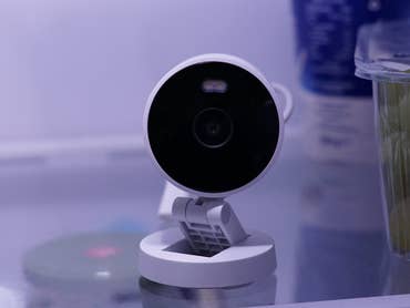 Aqara G100 Smart-Kamera auf einem Regal im Kühlschrank neben einem Behälter mit Trauben.