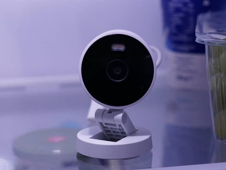 Aqara G100 Smart-Kamera auf einem Regal im Kühlschrank neben einem Behälter mit Trauben.