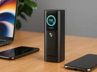 ASPERX 20000 mAh Powerbank auf einem Holztisch, mit zwei Smartphones und einem Laptop im Hintergrund.