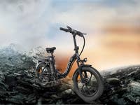 Ein schwarzes Avaka-E-Bike steht auf steinigem Terrain mit Bergen im Hintergrund.