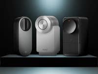 Drei intelligente Schlösser, die auf einem Sockel präsentiert werden, mit unterschiedlichen Designs und Farben, beleuchtet vor dunklem Hintergrund.