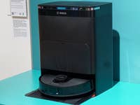 Bosch Spotless Roboterstaubsauger und Dockingstation auf einer türkisfarbenen Oberfläche.