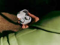 Bose QuietComfort-Ohrhörer in Weiß vor einem hellgrünen Hintergrund.