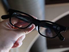Eine Hand, die Rokid-Smartgläser mit dunklen Gläsern hält.