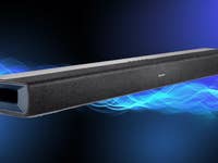 Denon DHT-S218 Soundbar mit elegantem Design vor einem blauen abstrakten Hintergrund.