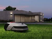 Ein Dreame A1 Pro Mähroboter auf grünem Gras vor einem modernen Haus bei Dämmerung.