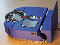 Dyson 360 Vis Nav Saugroboter in Blau mit sleek Design, auf einer Holzoberfläche präsentiert.