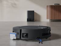 Ecovacs Deebot T80 Omni Saugroboter auf einem Betonboden, mit einer Ladestation im Hintergrund.