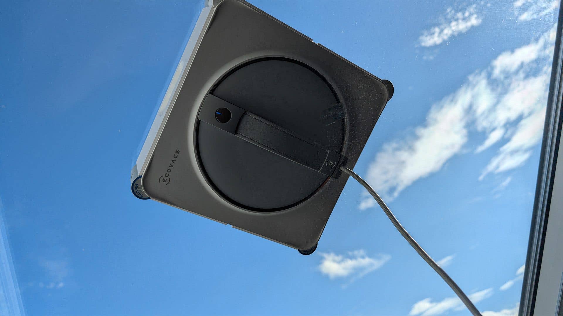 Ecovacs Winbot W2S Omni Fensterputzroboter auf einer Glasoberfläche mit blauem Himmel im Hintergrund.