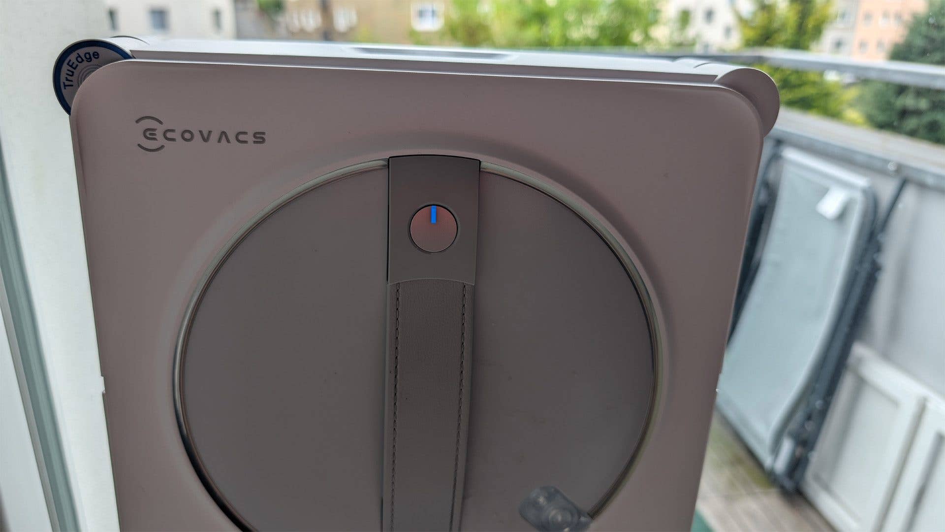 Nahaufnahme des Ecovacs Winbot W2S Omni Fensterputzroboters mit einem blauen Knopf.