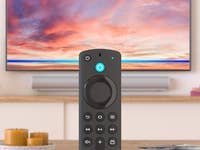 Fire TV Stick 4K Max im Vordergrund, ein Smart TV im Hintergrund