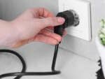 Frau nimmt Stecker aus der Steckdose