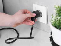 Frau nimmt Stecker aus der Steckdose