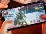 Gamer spielt das Spiel Apex Legends Mobile auf dem iPhone 13.