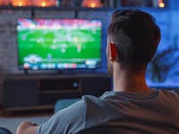 Man sitzt auf der Couch und schaut Fußball