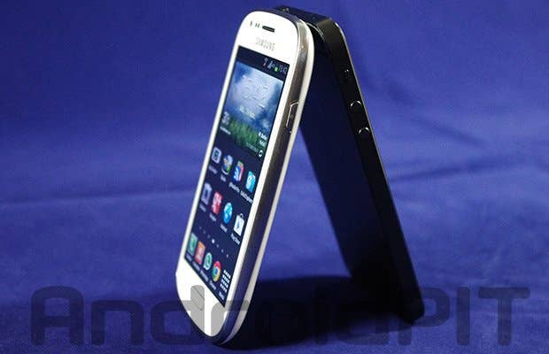 Zwei Smartphones, eines weiß und eines schwarz, stehen schräg zueinander auf einem blauen Hintergrund.