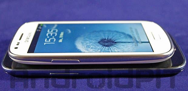 Ein weißes Smartphone mit einem Dandelion-Hintergrund liegt auf einem schwarzen Smartphone.