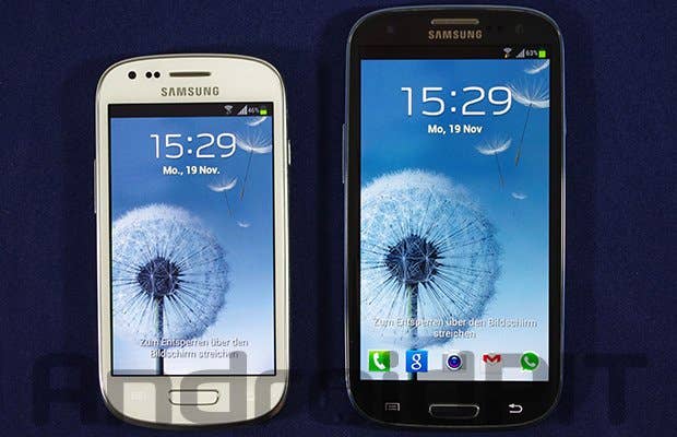 Zwei Samsung-Smartphones nebeneinander, eines in Weiß und das andere in Schwarz, beide mit dem Bildschirm an, der die Uhrzeit zeigt.