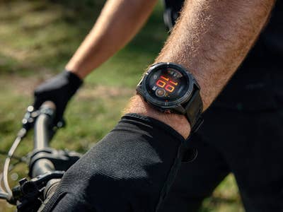 Nahaufnahme einer Garmin-Smartwatch, die Fitnessdaten am Handgelenk eines Radfahrers anzeigt.