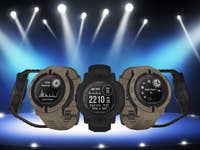 Drei Garmin Instinct 2 Solar Tactical-Uhren unter Scheinwerferlicht, die verschiedene Funktionen auf ihren Bildschirmen zeigen.