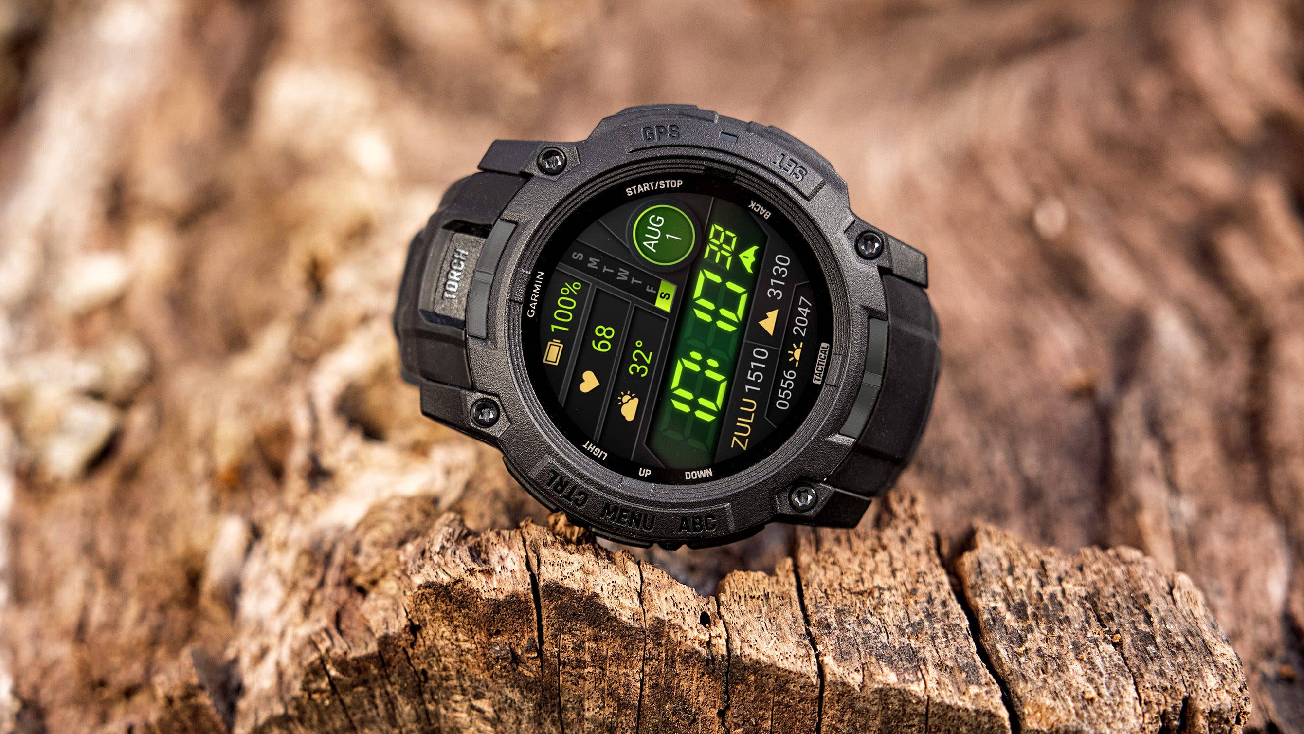 Garmin Instinct 3 Tactical Edition Uhr auf einer Holzoberfläche, die Uhrzeit, Herzfrequenz und Batteriestand anzeigt.
