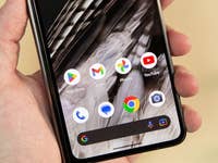 Eine Hand hält ein Smartphone, das Google Chrome und verschiedene App-Icons zeigt.
