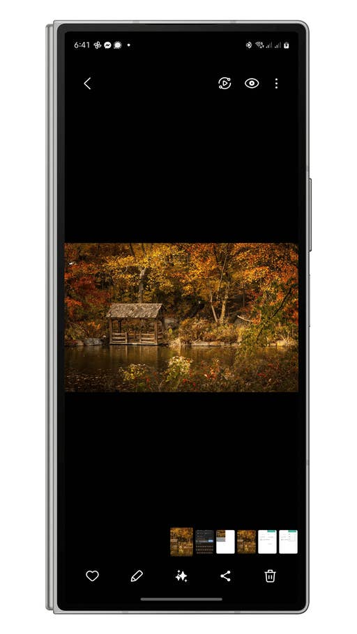 Eine kleine Holzstruktur an einem ruhigen See, umgeben von buntem Herbstlaub.