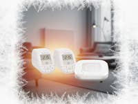 Zwei Homematic IP-Thermostate und ein Homematic IP-Zugangspunkt vor einem verschwommenen Innenhintergrund.