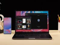 Ein Laptop, der einen digitalen Arbeitsplatz zeigt, neben einem Smartphone auf einem Schreibtisch mit Büromaterialien.