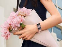 Eine Frau hält einen Strauß rosa Blumen und trägt eine Huawei Watch Fit SE am Handgelenk.