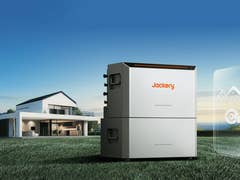 Jackery HomePower 2000 Ultra-Gerät in einem grasbewachsenen Bereich mit einem modernen Haus im Hintergrund.