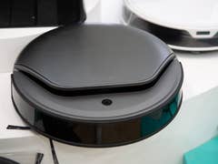 Ein schwarzer, robotischer Staubsauger, der ausgestellt ist, mit einem eleganten Design und glänzender Oberfläche.