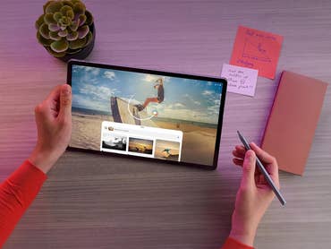 Eine Person benutzt ein Lenovo IdeaTab Pro Tablet mit einem Stylus, studiert mit Notizen und einer Pflanze auf dem Tisch.