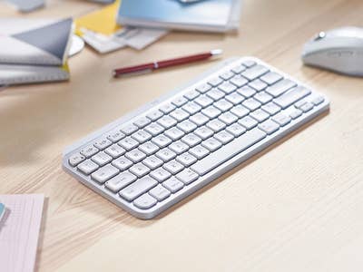 Eine Logitech MX Keys Mini-Tastatur für Mac auf einem Holztisch mit Schreibwaren.