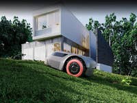 Ein Mähroboter auf einem grasbewachsenen Hang neben einem modernen Haus.
