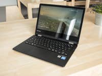 Ein Medion Akoya E2228T Laptop ist auf einem Holztisch geöffnet und zeigt die Uhrzeit sowie eine malerische Hintergrundansicht.