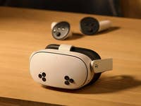 Ein Meta Quest 3S VR-Headset auf einer Holzoberfläche mit zwei Controllern im Hintergrund.