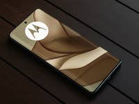 Ein Motorola Edge 50 Smartphone auf einer Holzoberfläche, dessen Bildschirm ein Design und das Motorola-Logo zeigt.
